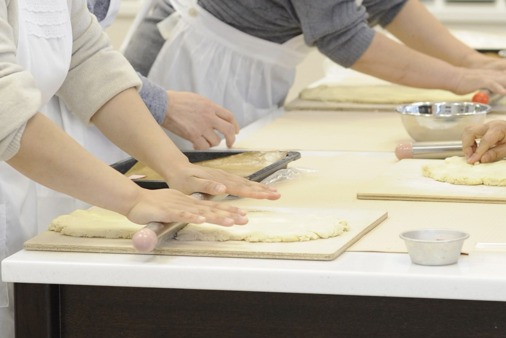 パン作りの材料の役割を学び作業台で丁寧に生地を伸ばし成形するスクールの講習風景