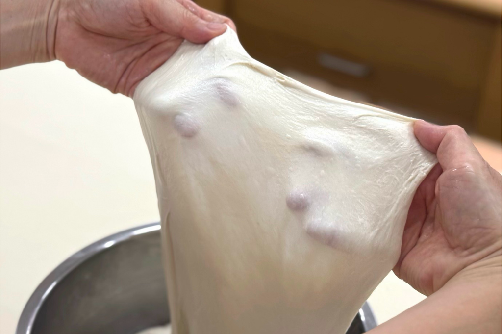 パン作りの失敗を防ぐためこね上がり状態の指が透けるほど薄く伸びる綺麗なグルテン膜を確認する様子